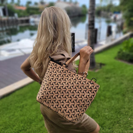Woman holding a patterned handbag by a waterfront