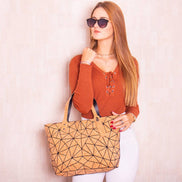 Woman holding a geometric-patterned tote bag against a plain background