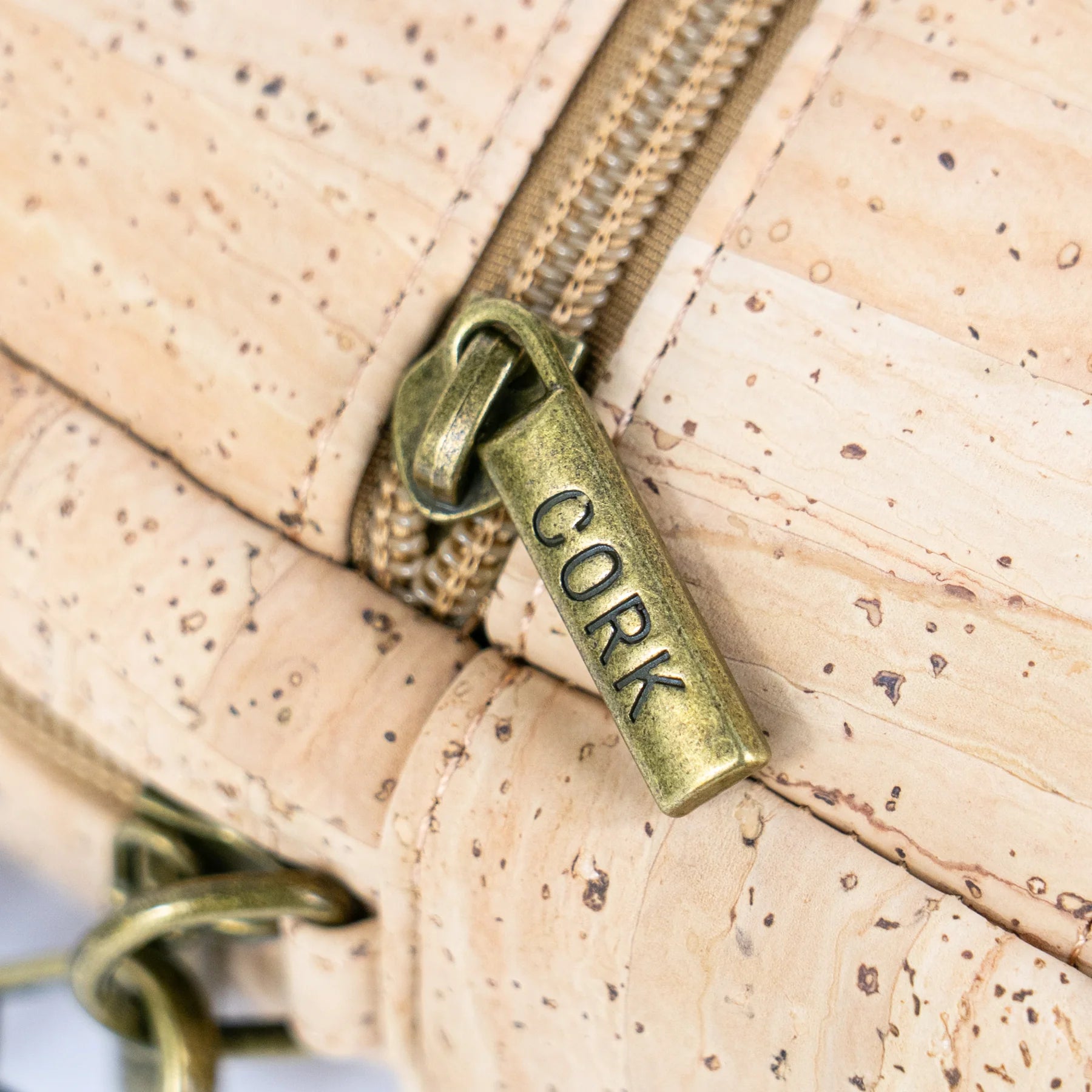 Close up view of antique brass zipper on cork crossbody bag
